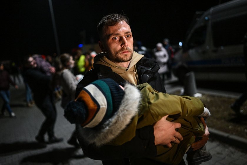 Άντρας αγκαλιά με το μωρό του, καθώς διασχίζει τα σύνορα με την Ουκρανία στην πόλη Przemysl της Πολωνίας (Φωτογραφία: GETTY IMAGES)